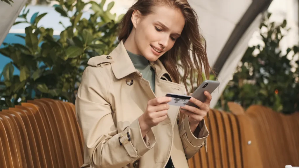 Studentka z kartą płatniczą i smartfonem płaci w aplikacji banku podczas przerwy między zajęciami